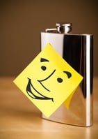 Drawn smiley face on a post-it note sticked on a hip flask